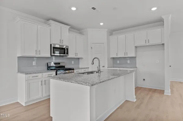 a kitchen with kitchen island granite countertop a sink cabinets and wooden floor