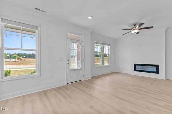 a view of an empty room with a window and wooden floor