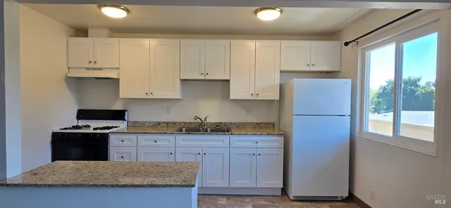 a kitchen with granite countertop a sink a stove and refrigerator