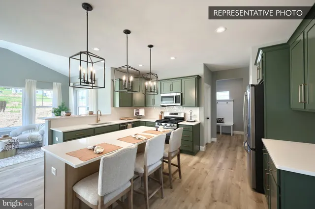 a kitchen with stainless steel appliances granite countertop a sink a stove a refrigerator and chairs