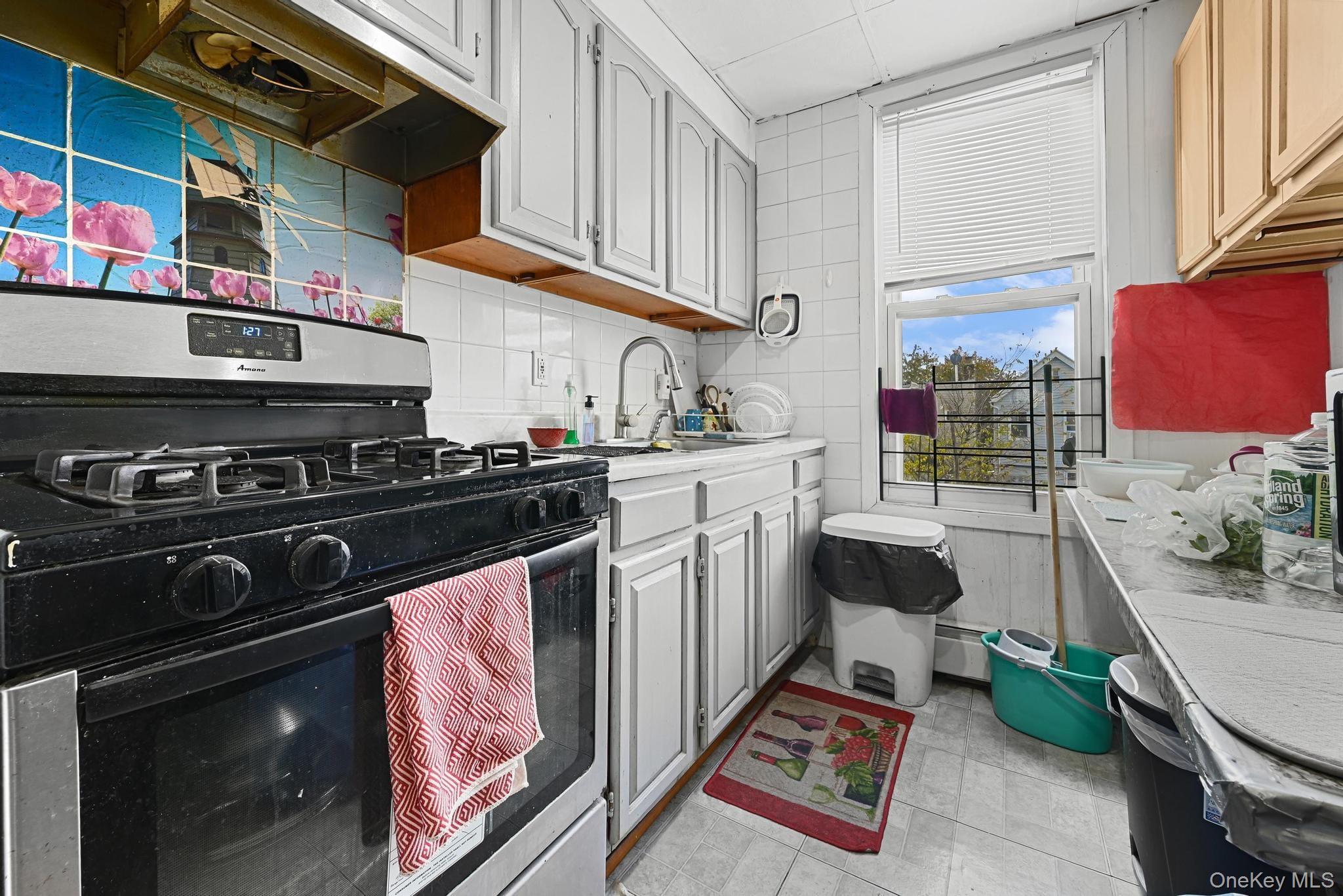 90-16 76th Street Queens, NY 11421 - Photo 5 of 28 a kitchen with stainless steel appliances a stove a sink and a microwave