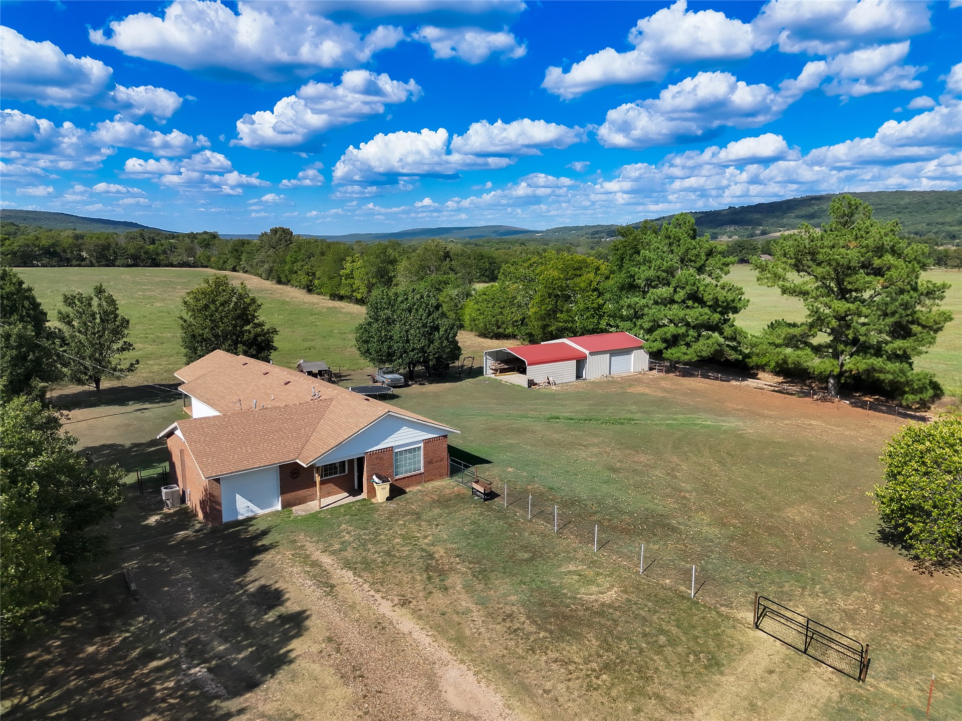 81232 South 4775 Road Stilwell, OK 74960 - Photo 2 of 50 Brick exterior home with a shingle roof, accompanied by a detached metal-roofed outbuilding