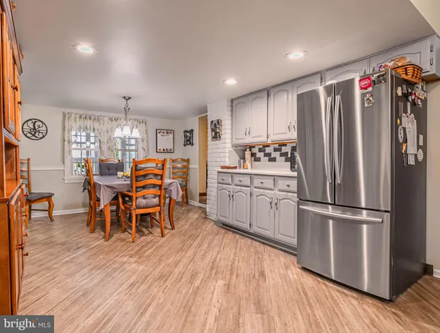 a kitchen with stainless steel appliances a dining table chairs refrigerator and wooden floor