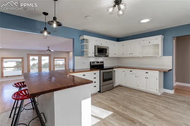 a kitchen with stainless steel appliances granite countertop a stove top oven a sink a dining table and chairs with wooden floor