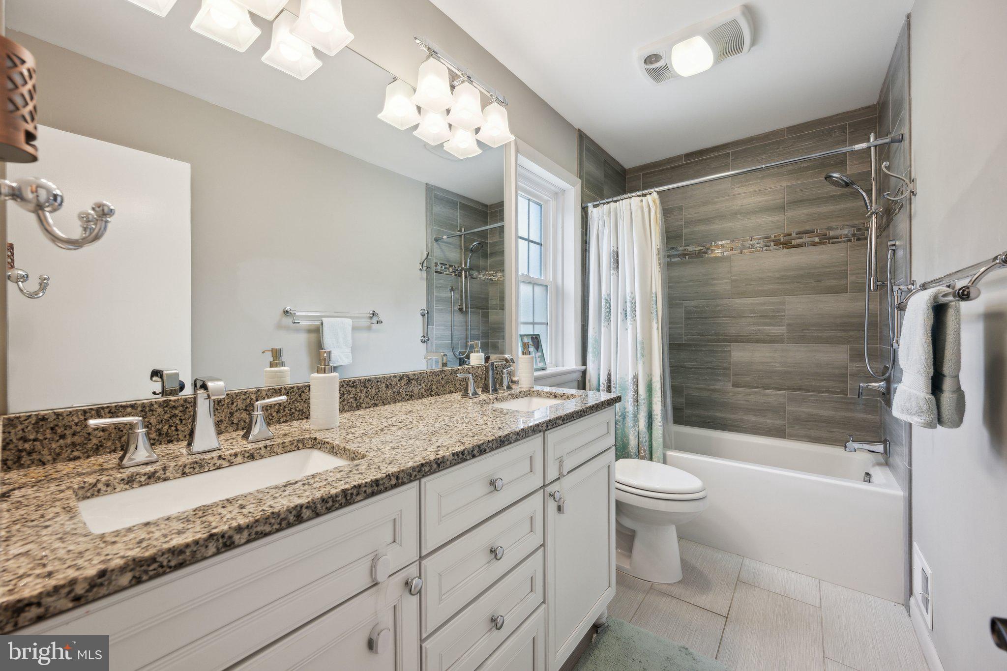 10601 Meadowhill Road Silver Spring, MD 20901 - Photo 17 of 33 a bathroom with a granite countertop sink a toilet a mirror a bathtub and shower