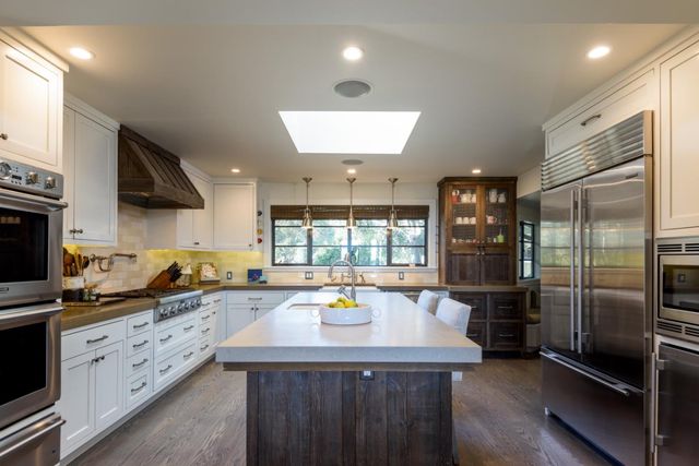 a kitchen with stainless steel appliances granite countertop a sink a stove and a refrigerator