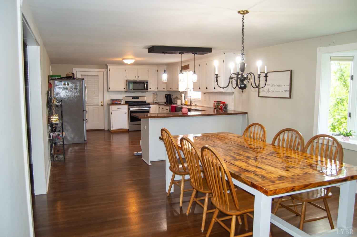 4740 Payneton Road Chatham, VA 24531 - Photo 27 of 49 a kitchen with stainless steel appliances granite countertop a kitchen island a stove a dining table and chairs with wooden floor