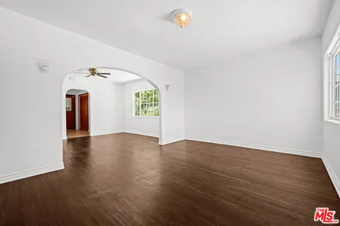 a view of an empty room with window and wooden floor