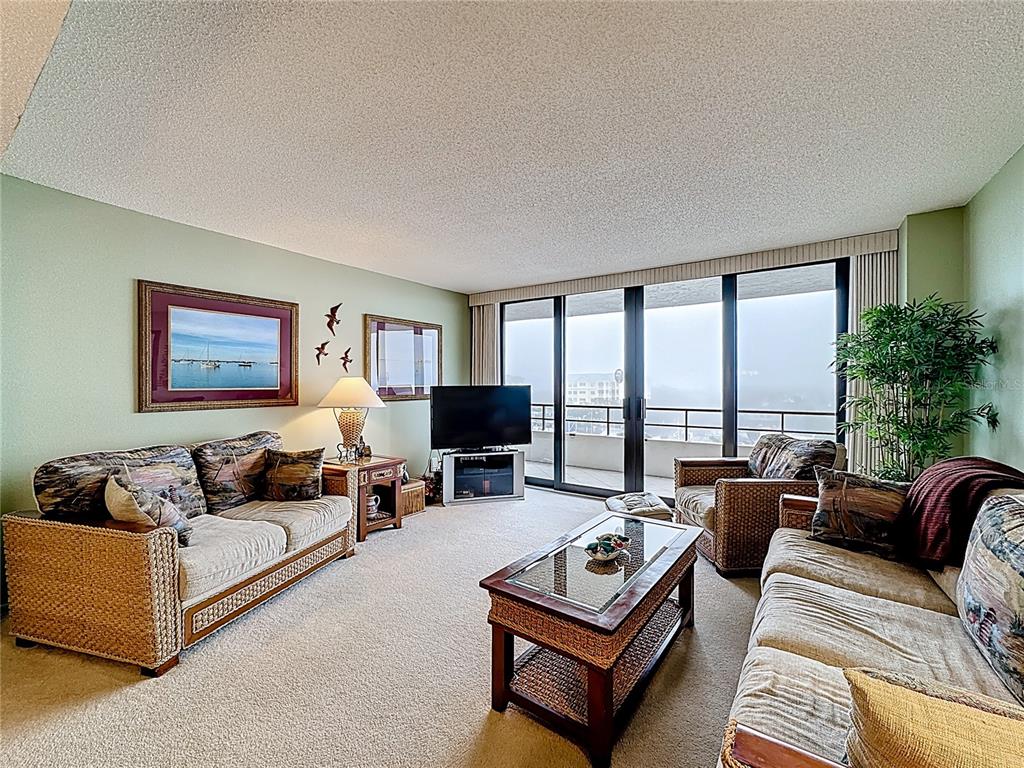 6415 Midnight Pass Road, Unit 705 Sarasota, FL 34242 - Photo 13 of 44 a living room with furniture large windows and a flat screen tv