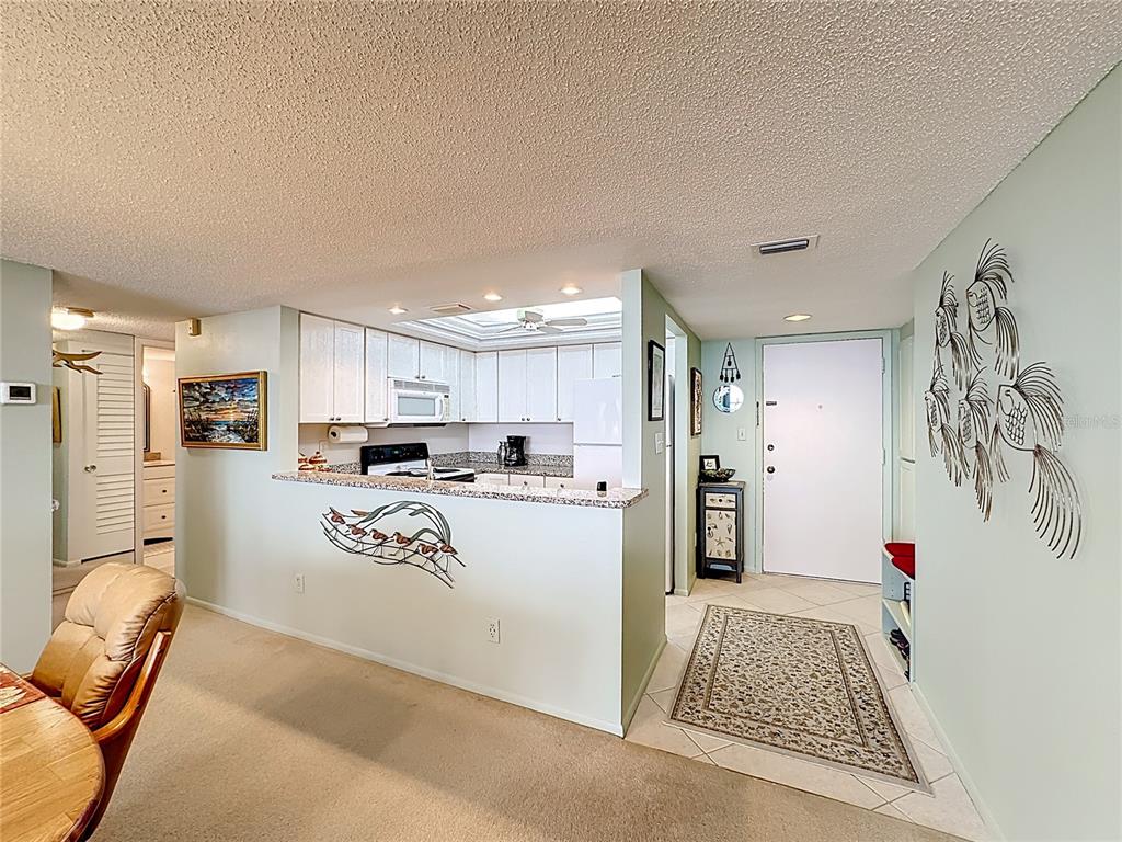 6415 Midnight Pass Road, Unit 705 Sarasota, FL 34242 - Photo 6 of 44 a kitchen with stainless steel appliances kitchen island granite countertop a refrigerator and a sink