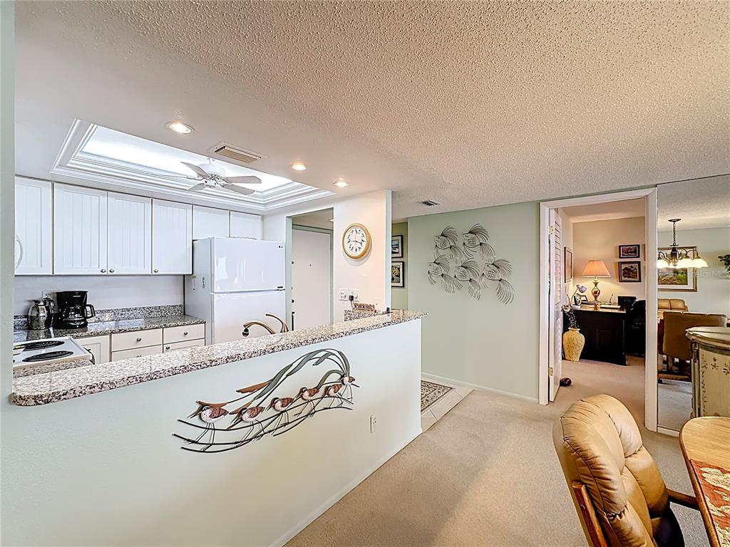 6415 Midnight Pass Road, Unit 705 Sarasota, FL 34242 - Photo 8 of 44 a kitchen with granite countertop white cabinets and refrigerator