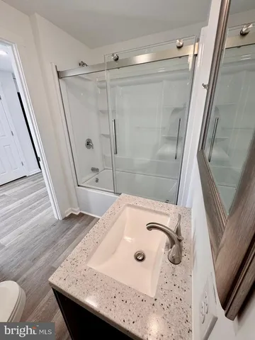 a bathroom with a granite countertop sink a mirror and shower