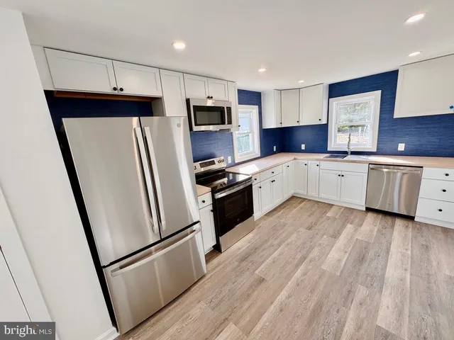 a kitchen with white cabinets and stainless steel appliances