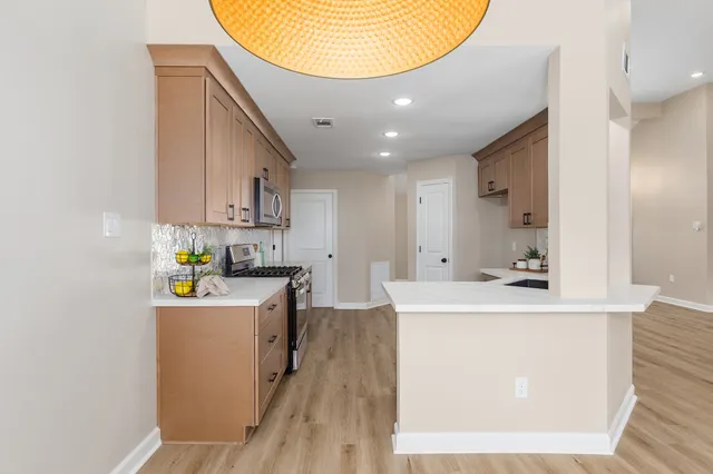 a kitchen with kitchen island stainless steel appliances a sink a stove top oven a counter space and cabinets