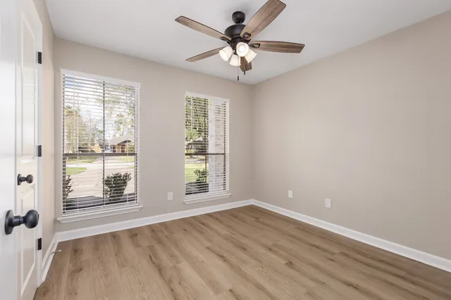 an empty room with wooden floor and windows