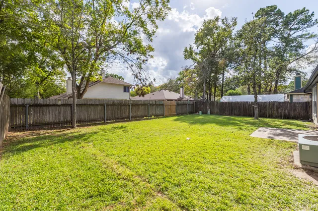 a view of a backyard with a large tree and wooden fence
