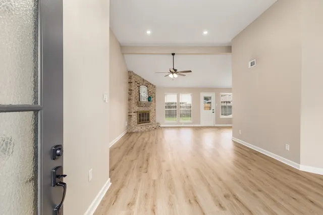 an empty room with wooden floor and windows