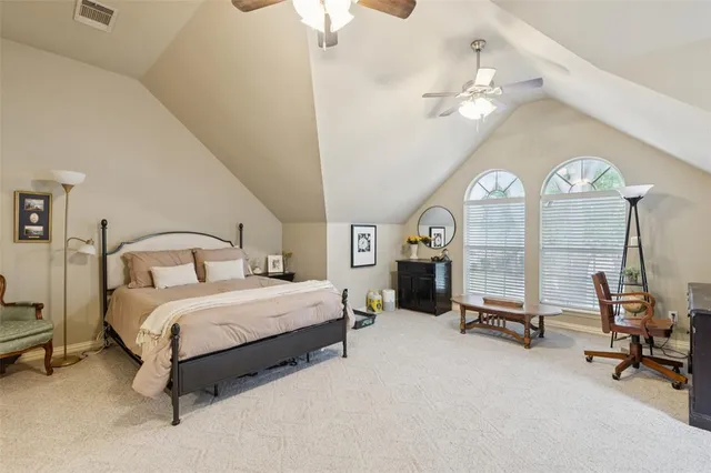 a spacious bedroom with a bed a chandelier and large mirror on the dresser