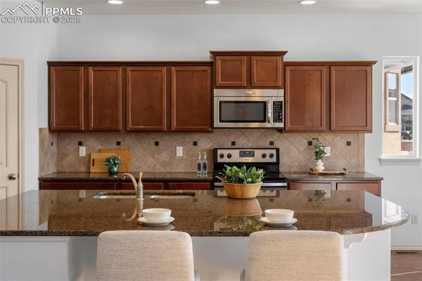 a kitchen with granite countertop a stove a sink a microwave and cabinets