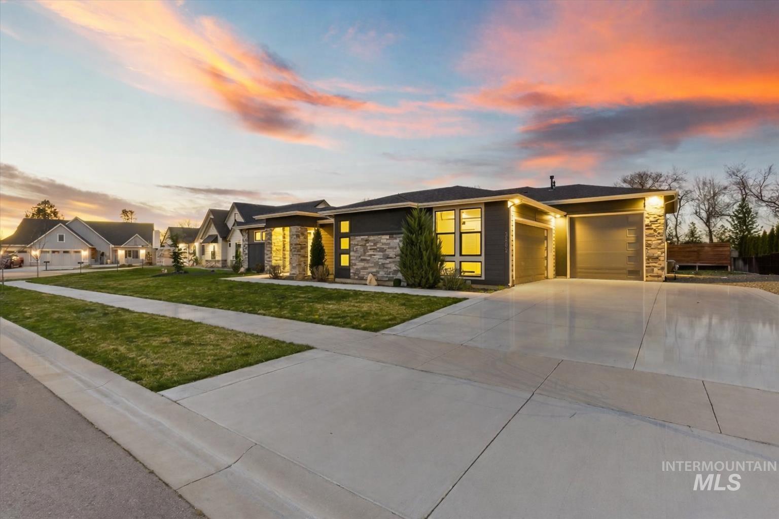 Prairie-style house with stone siding, an attached garage, concrete driveway, and a yard