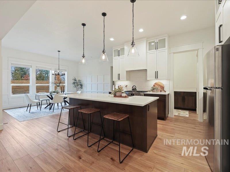 3882 West Haverhill Street Eagle, ID 83616 - Photo 12 of 41 Kitchen with glass insert cabinets, freestanding refrigerator, dark brown cabinets, pendant lighting, and white cabinetry