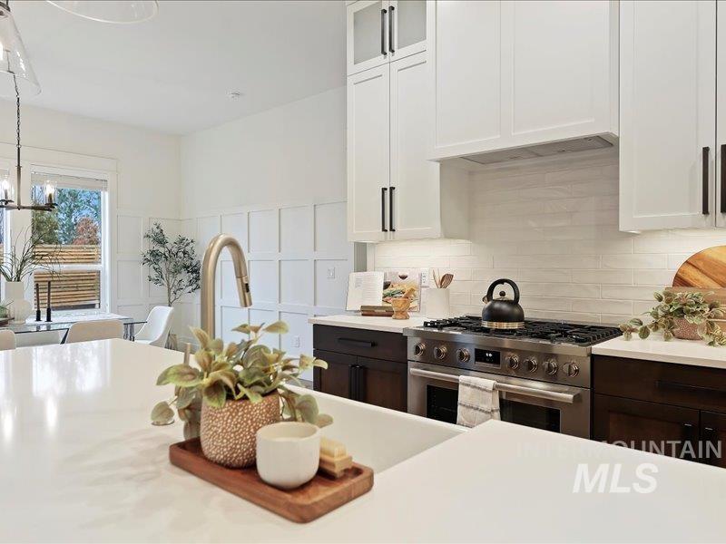 3882 West Haverhill Street Eagle, ID 83616 - Photo 14 of 41 Kitchen with white cabinetry, high end stainless steel range, glass insert cabinets, dark brown cabinetry, and a decorative wall