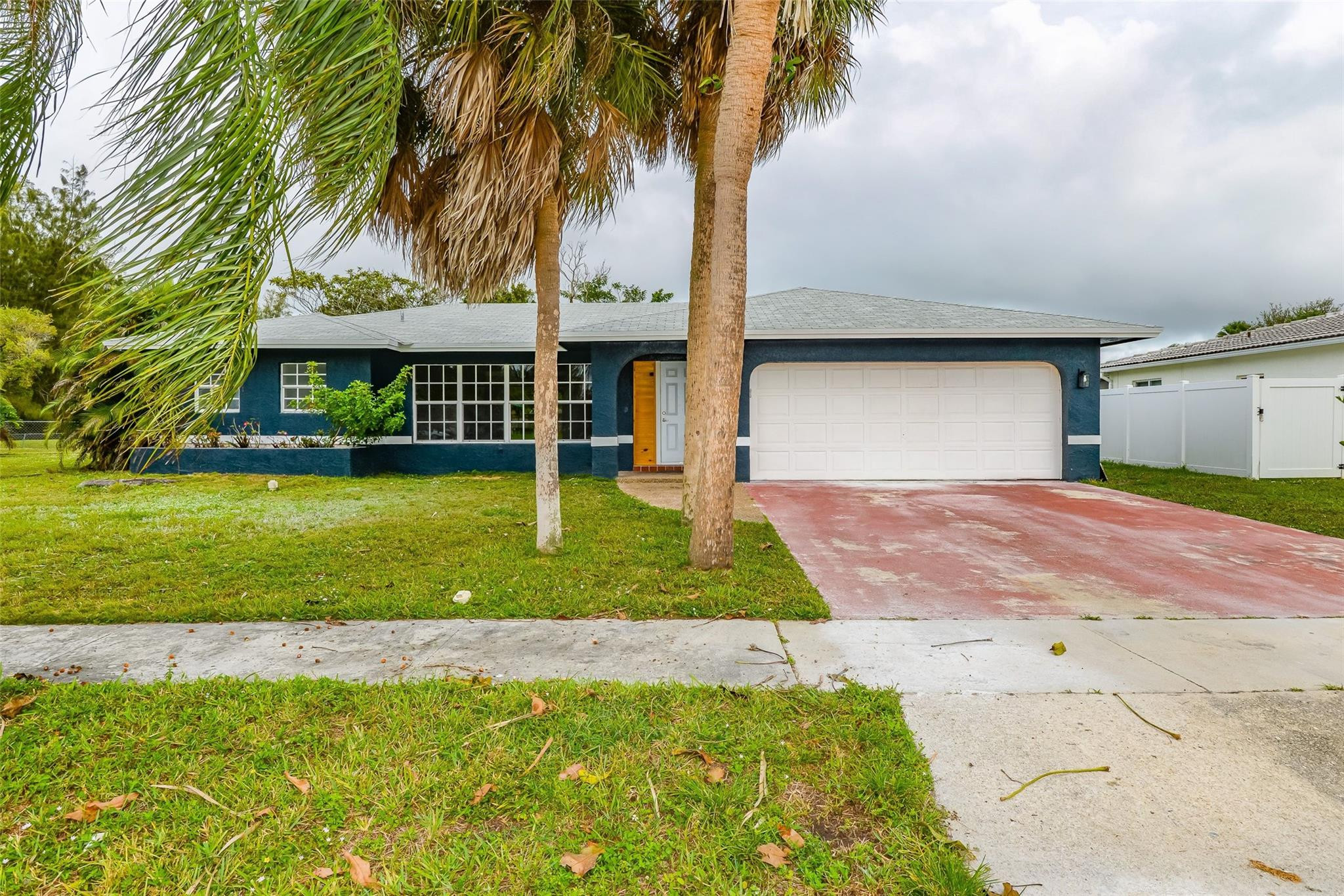 a front view of a house with a yard and palm trees