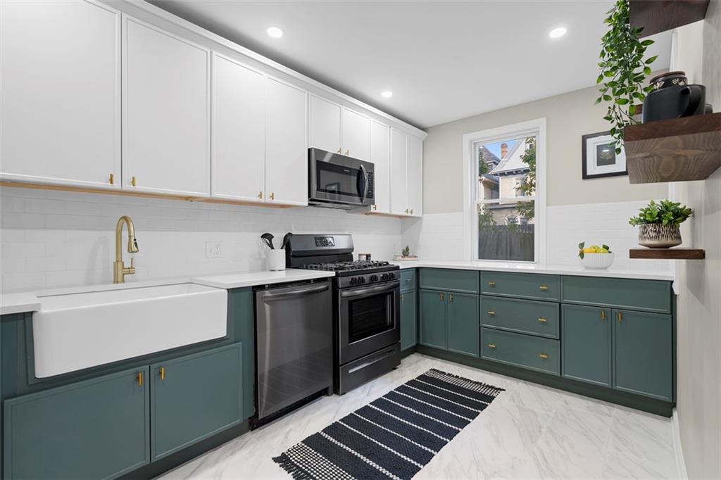 411 Kambach Street Pittsburgh, PA 15211 - Photo 16 of 47 Large Galley style Kitchen is a stunner featuring shaker cabinets galore, quartz countertops, large farm style sink, excellent natural light, ceramic tile flooring, and stainless steel appliances!