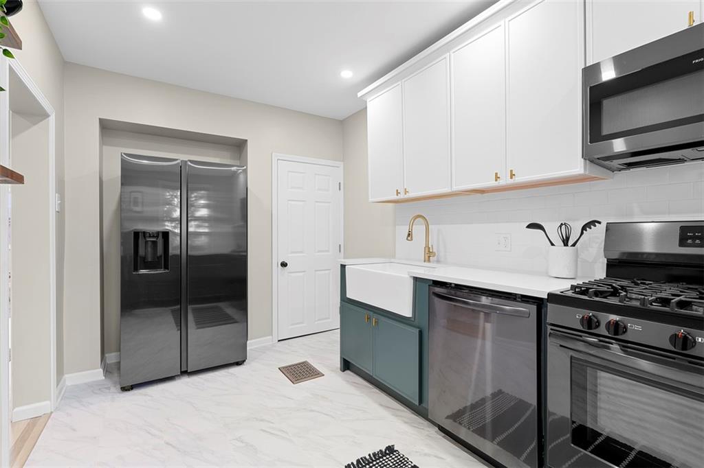 411 Kambach Street Pittsburgh, PA 15211 - Photo 20 of 47 Large Galley style Kitchen is a stunner featuring shaker cabinets galore, quartz countertops, large farm style sink, excellent natural light, ceramic tile flooring, and stainless steel appliances!