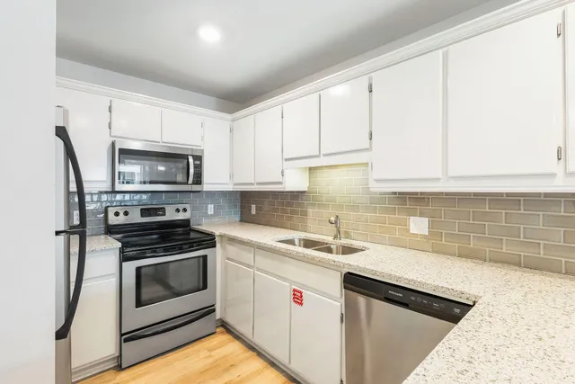 a kitchen with white cabinets stainless steel appliances and sink
