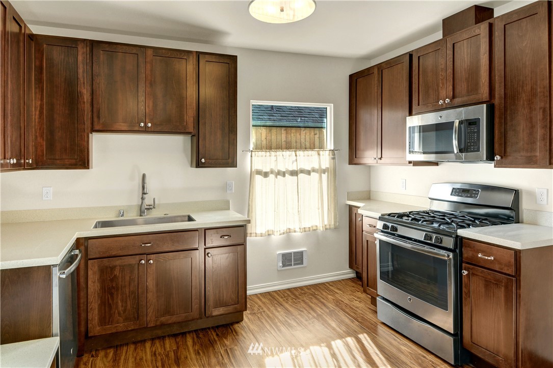 834 15th Avenue Seattle, WA 98122 - Photo 15 of 23 a kitchen with granite countertop wooden cabinets and a stove top oven