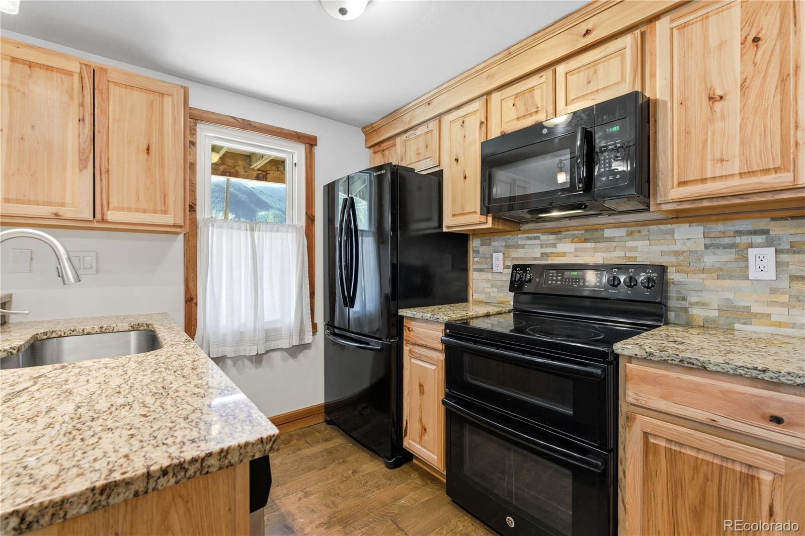 1463 Main Street Georgetown, CO 80444 - Photo 18 of 47 a kitchen with stainless steel appliances granite countertop a stove microwave refrigerator and sink