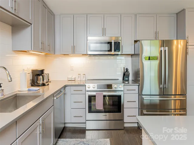 a kitchen with stainless steel appliances granite countertop a refrigerator stove a sink and dishwasher with white cabinets