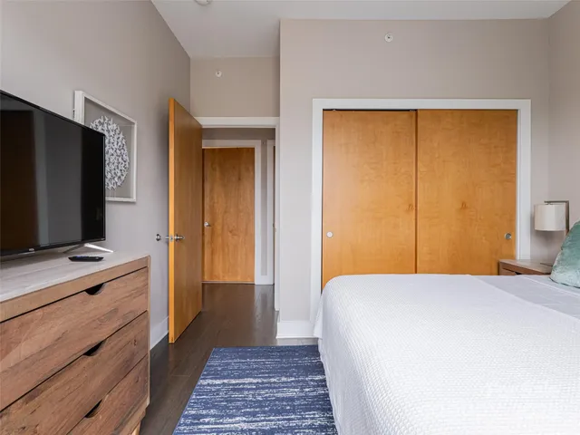 a bedroom with a bed and a flat tv screen on dresser