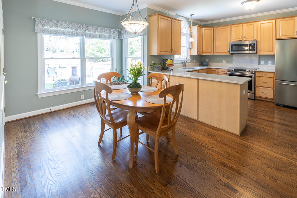5924 North Hawthorne Way Raleigh, NC 27613 - Photo 13 of 45 a kitchen with stainless steel appliances granite countertop wooden floor dining table and chairs