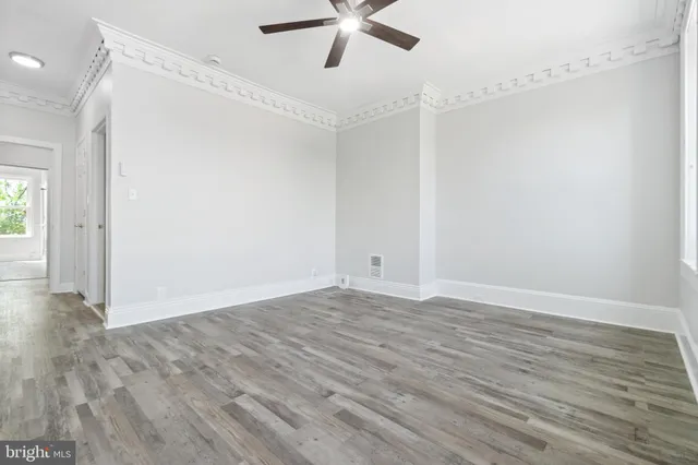 a view of empty room with wooden floor and fan