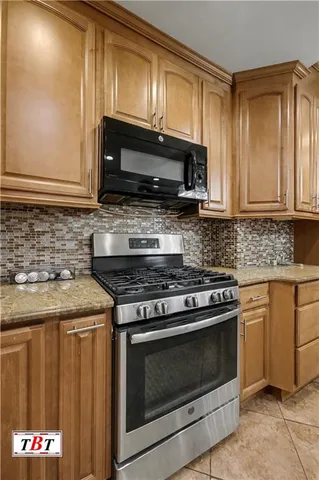 a kitchen with granite countertop a stove top oven microwave and cabinets