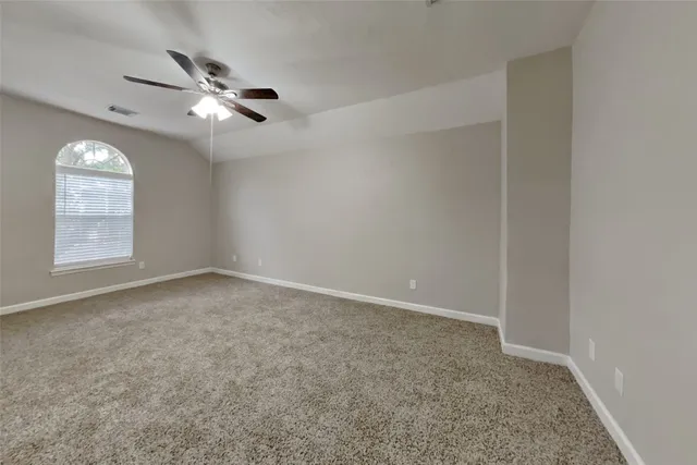 an empty room with a chandelier fan and windows