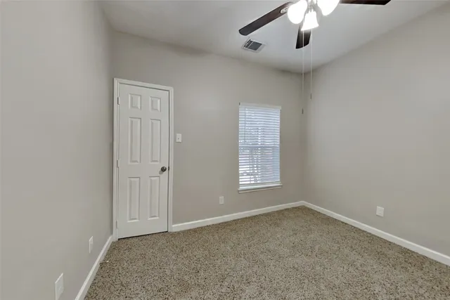 an empty room with a chandelier fan and windows