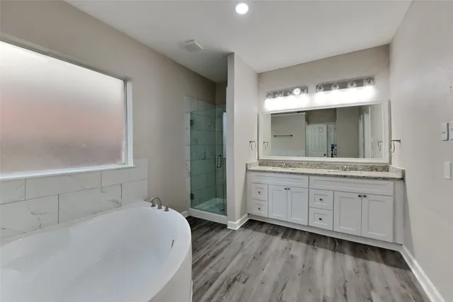 a spacious bathroom with a granite countertop sink mirror and a bathtub