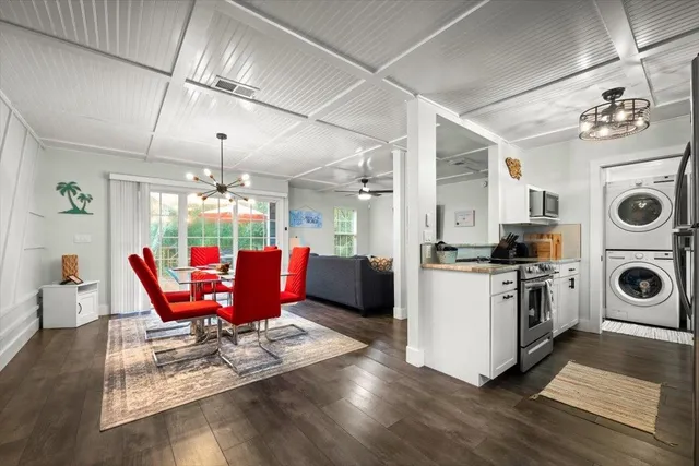 a kitchen with stainless steel appliances granite countertop a stove top oven a refrigerator a dining table and chairs with wooden floor