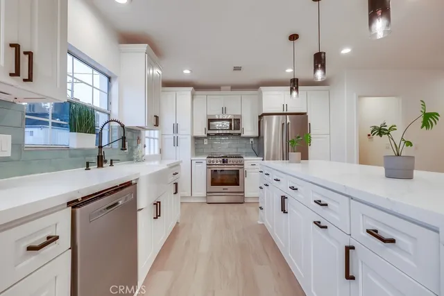 a kitchen with stainless steel appliances granite countertop a refrigerator a sink dishwasher a stove and a refrigerator