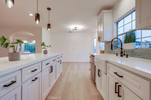 a kitchen with stainless steel appliances granite countertop a sink a stove top oven and a wooden floors