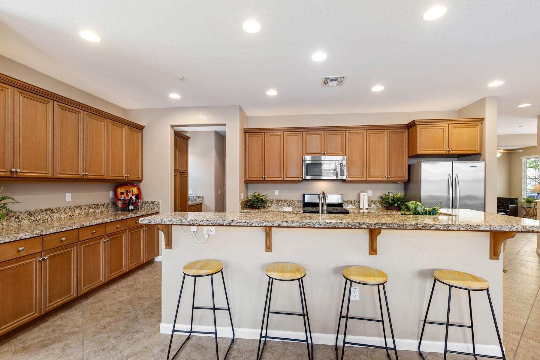 9901 Pyramid Way Discovery Bay, CA 94505 - Photo 16 of 53 a kitchen with stainless steel appliances granite countertop a stove top oven a sink a refrigerator and white cabinets with wooden floor