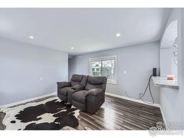 a kitchen with granite countertop a refrigerator oven a sink dishwasher and white cabinets with wooden floor