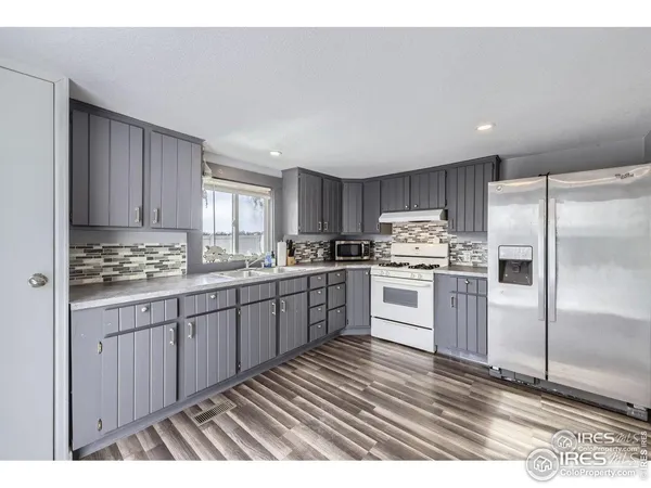 a kitchen with granite countertop a refrigerator cabinets and wooden floor