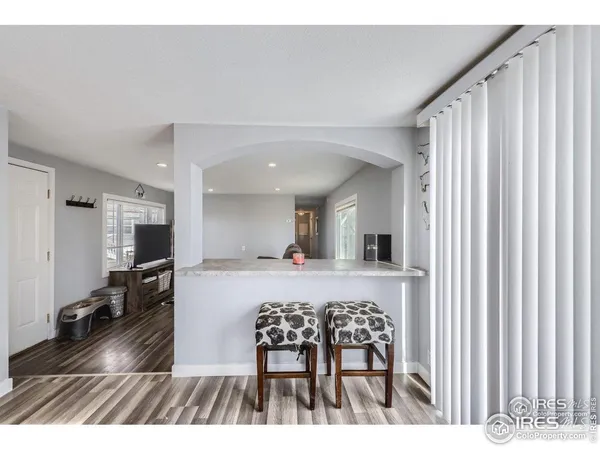 a living room with stainless steel appliances kitchen island granite countertop a refrigerator a stove and a sink with wooden floor
