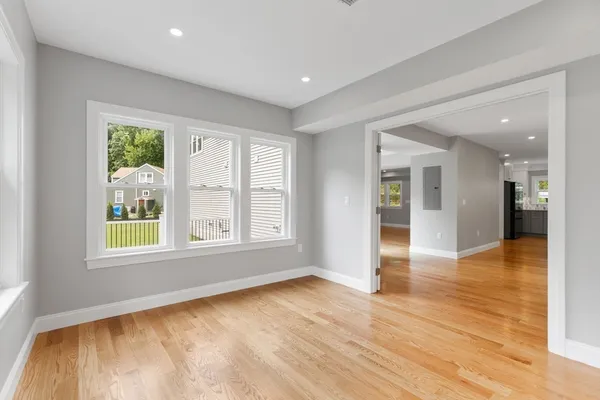 a view of an empty room with wooden floor and a window