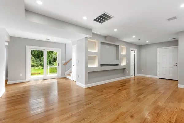 a view of an empty room with a window and wooden floor