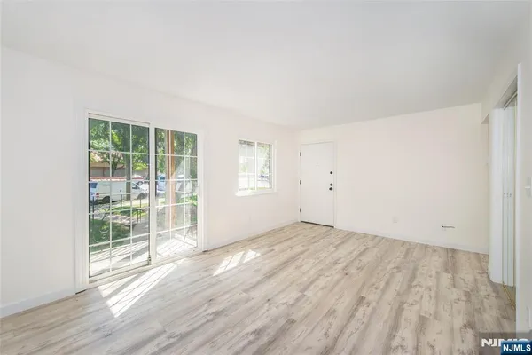an empty room with wooden floor a chandelier fan and windows